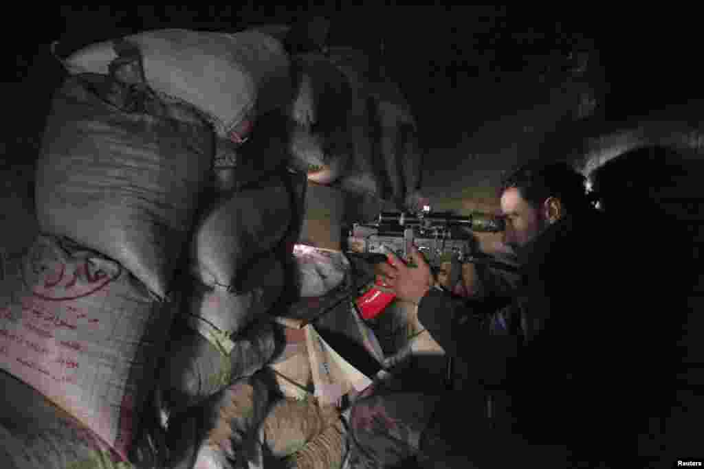 A Syrian army soldier loyal to President Bashar al-Assad points his weapon through piled sandbags at the justice palace in the old city of Aleppo, Feb. 10, 2014.