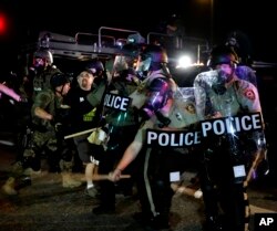 A man is detained after a standoff between protesters and police Monday, Aug. 18, 2014.