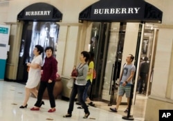 2012年6月，顾客走出英国奢侈品制造商博伯利（Burberry）在上海开设的分店。如今不少消费者花钱不再大手大脚