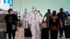 FILE - Air China flight crew members in hazmat suits walk through the arrivals area at Los Angeles International Airport in Los Angeles, Nov. 30, 2021.