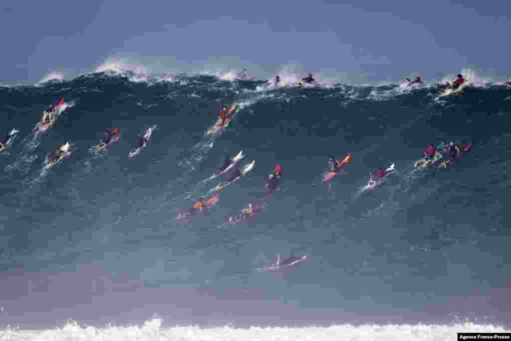 Surfers paddle out to catch waves at Waimea Bay, Hawaii.