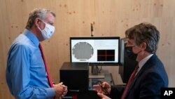FILE - In this April 28, 2021 file photo, New York Mayor Bill de Blasio, left, speaks with Matthew Putman, co-founder and CEO of Nanotronics, during a facility tour before a ribbon-cutting ceremony to mark the opening of a Nanotronics manufacturing facility.