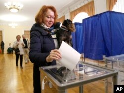 A woman holds a pet and casts her ballot at a polling station during the presidential election in Kyiv, Ukraine, March 31, 2019.