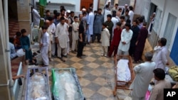 FILE - Pakistani Shi'ite Muslims gather around bodies of the victims of a suicide bombing for which the Sunni militant group Lashkar-e-Jhangvi claimed responsibility in Quetta, Pakistan, July 1, 2013.