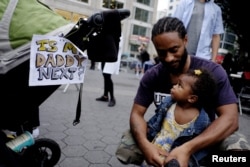 A man and child take part in a march supporting the Black Lives Matter movement along the streets of Manhattan in New York, July 8, 2016. A sign affixed to a stroller asks, “Is my daddy next?”