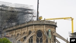 Experts prepare to remove a statue from the damaged Notre Dame cathedral after the fire in Paris, Tuesday, April 16, 2019. (AP Photo/Michel Euler)