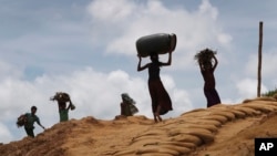 FILE - Rohingya girls carry firewood on their heads as they make their way through Kutupalong refugee camp, June 28, 2018, in Bangladesh.