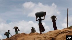 FILE - Rohingya girls carry firewood on their heads as they make their way through Kutupalong refugee camp, June 28, 2018, in Bangladesh.