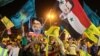 Hezbollah supporters wave Hezbollah and Syrian flags with a picture of Syrian President Bashar al-Assad, right, and Hezbollah leader Sheik Hassan Nasrallah, left, during a rally marking the sixth anniversary of the 2006 Israel-Hezbollah war, in Beirut, Le