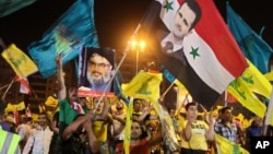 Hezbollah supporters wave flags and pictures of Syrian President Bashar al-Assad and Hezbollah leader Sheik Hassan Nasrallah during a rally marking the sixth anniversary of the 2006 Israel-Hezbollah war, in Beirut, July 18, 2012.