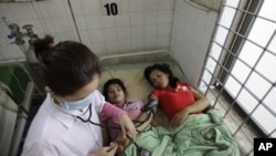 A Cambodian doctor checks blood pressure of survivors of November 22's stampede at Preah Kossamak Hospital in Phnom Penh.