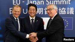 FILE - Japan's Prime Minister Shinzo Abe, center, is welcomed by European Council President Donald Tusk, left, and European Commission President Jean-Claude Juncker at the start of a European Union-Japan summit in Brussels, July 6, 2017.