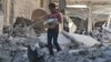 A boy carries bread as he makes his way through rubble of a site hit by an airstrike in the rebel-held area of Aleppo's al-Sukari district, Syria, May 30, 2016. 