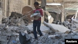 A boy carries bread as he makes his way through rubble of a site hit by an airstrike in the rebel-held area of Aleppo's al-Sukari district, Syria, May 30, 2016. 