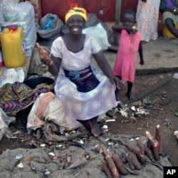 A female vendor, with her child looking on, offers produce at a roadside market in Ghana.