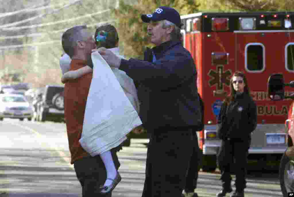 Seorang anak perempuan segera diberi selimut setelah dievakuasi dari SD Sandy Hook pasca terjadinya penembakan di Newtown, Connecticut, 14 Desember 2012.