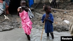 Children walk through mud in an internally displaced persons camp inside the United Nations base in Malakal, South Sudan, July 23, 2014.