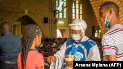 Une catholique reçoit la Sainte Communion à la cathédrale Notre-Dame du Congo à Kinshasa le 16 août 2020 lors de la première messe célébrée depuis le 24 mars, en raison de la pandémie COVID-19.