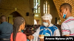 Une catholique reçoit la Sainte Communion à la cathédrale Notre-Dame du Congo à Kinshasa le 16 août 2020 lors de la première messe célébrée depuis le 24 mars, en raison de la pandémie COVID-19.