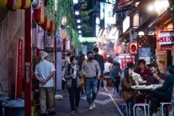 Warga mengenakan masker sebagai tindakan pencegahan terhadap virus Covid-19 saat mengunjungi kawasan restoran Omoide Yokocho di distrik Shinjuku, Tokyo, 19 November 2020.