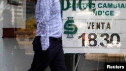A man walks in front of a board displaying the exchange rate for Mexican peso and U.S. dollars at a foreign exchange house in Mexico City, Mexico, Oct. 20, 2017.