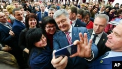 Ukrainian President Petro Poroshenko takes a selfie with students during his visit to the university in Kiev, Ukraine, Monday, March 25, 2019. Presidential vote in Ukraine is to take place on March 31. (Mykola Lazarenko/Presidential Press Service Pool Photo via AP)