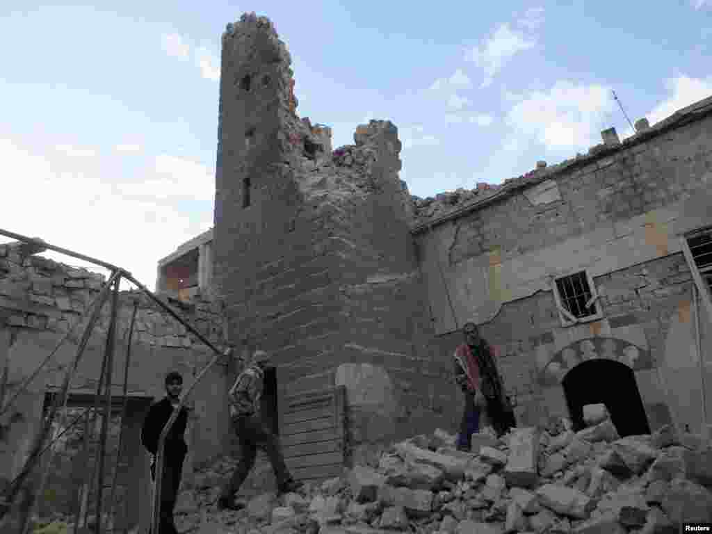 Men walk on the rubble of a damaged mosque in the besieged area of Homs, Jan. 30, 2014. 