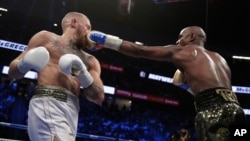 Floyd Mayweather Jr. jabs Conor McGregor in a super welterweight boxing match, Aug. 26, 2017, in Las Vegas.