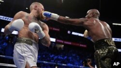 ທ້າວ Floyd Mayweather Jr. ຍິງໝັດແຢັບໃສ່ທ້າວ Conor McGregor ໃນການຊົກມວຍລຸ້ນນໍ້າໜັກບໍ່ເກີນ 60 - 61.6 ກິໂລກຣາມ. 26 ສິງຫາ, 2017, ທີ່ເມືອງ Las Vegas.