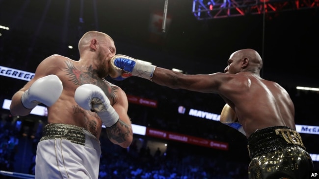 FILE - Floyd Mayweather Jr. jabs Conor McGregor in a super welterweight boxing match, in Las Vegas, Aug. 26, 2017.