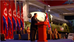Kim Yong Un duke mbajtur një fjalim ndërsa në sfond shfaqen raketa