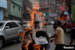 Venezuelan pro-government supporters set fire to an effigy of U.S. President Donald Trump, shown with photos of Argentine President Mauricio Macri, left, and National Assembly leader Julio Borges in Caracas’ Enero neighborhood, April 16, 2017.