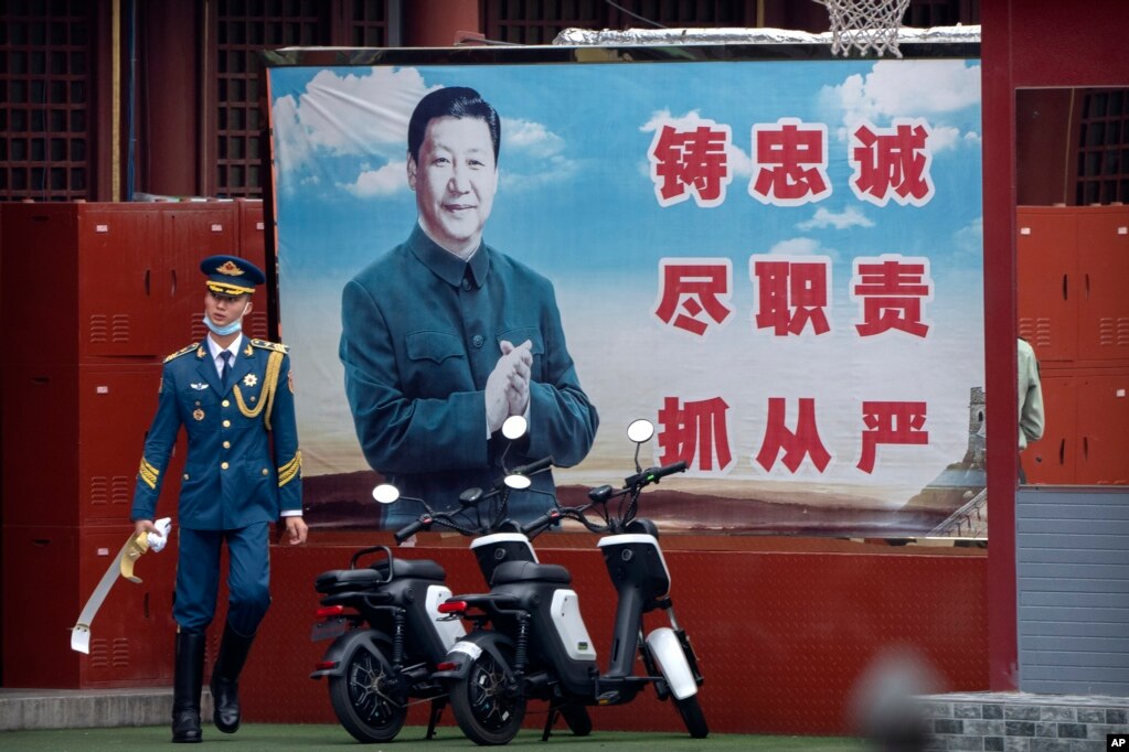 资料照片：在北京紫禁城入口附近，一名仪仗兵走过巨幅习近平宣传标语牌。(2021年9月18日)(photo:VOA)