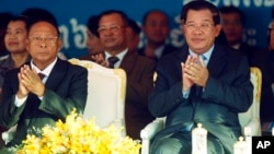 Cambodian Prime Minister Hun Sen, front right, applauses together with the National Assembly President Heng Samrin, front left, during an event by the ruling Cambodian People's Party, file photo. 
