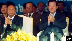 Cambodian Prime Minister Hun Sen, front right, applauses together with the National Assembly President Heng Samrin, front left, during an event by the ruling Cambodian People's Party marking the 36th anniversary of the 1979 downfall of the Khmer Rouge reg