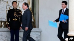 French President Francois Hollande, center, and Prime Minister Manuel Valls, right, walk through the lobby of the Elysee Palace after the weekly cabinet meeting, in Paris, Nov. 18, 2015. 