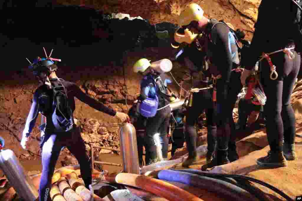 In this undated photo released by Royal Thai Navy on Saturday, July 7, 2018, Thai rescue team members walk inside a cave where 12 boys and their soccer coach have been trapped since June 23, in Mae Sai, Chiang Rai province, northern Thailand.