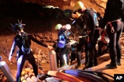 In this undated photo released by Royal Thai Navy on Saturday, July 7, 2018, Thai rescue team members walk inside a cave where 12 boys and their soccer coach have been trapped, in Mae Sai, Chiang Rai province, northern Thailand.