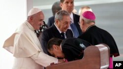 က်ဴးဘားခရစ္ယာန္အသင္းေတာ္အႀကီးအကဲက သမၼတ Raul Castro နဲ႔အတူ ရပ္ေနတဲ့ ပုပ္ရဟန္းမင္းႀကီး Francis ရဲ႕လက္ကို နန္း႐ႈတ္ႏႈတ္စဥ္။ (စက္တင္ဘာ ၁၉၊ ၂၀၁၅)