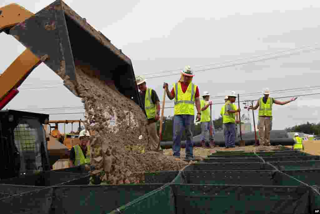 Workers fill Hesco baskets at a flood wall at Route 23, in advance of Tropical Storm Isaac in Plaquemines Parish, La., Aug. 28, 2012. 