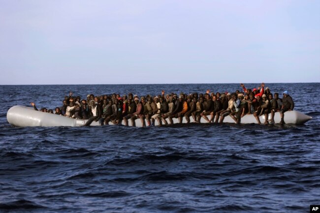 Sub-Saharan migrants crowd a rubber boat as they are rescued by members of Proactive Open Arms NGO, in the Mediterranean Sea, about 22 miles north of Zumarah, Libya, Jan. 27, 2017. Italy's coast guard, meanwhile, says it picked up about 1,000 migrants.