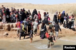 Displaced people, who fled from their homes in Hawija, cross the water to reach the other bank to be transported to camps for displaced people, in southwest of Kirkuk, Iraq, Oct. 4, 2017.