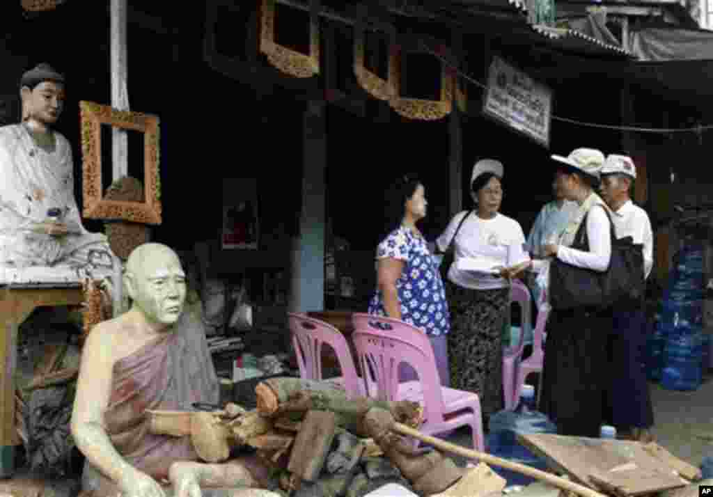 Myanmar census enumerators ask questions to a shop-owner as they collect information Sunday, March 30, 2014, in Yangon, Myanmar. Enumerators fanned out across Myanmar on Sunday for a census that has been widely criticized for stoking religious and ethnic