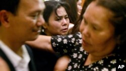 Chen Kasanoy, center, watches as her husband, Mike Bunthung, left greets and comforts family members and friends at the funeral for their slain son Woodtee Bunthung Sunday, Jan. 11, 2004, in Long Beach, Calif. Six young Cambodian-American men, including a Marine just back from Iraq, have died since late October in a rash of suspected gang-related violence in Long Beach, home to the largest concentration of Cambodians outside Phnom Penh. Police say at least three of thevictims had gang affiliations; the others may have been cases of mistaken identity. (AP Photo/Ric Francis)