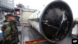 A South Korean sailor stands guard near a part of debris from a rocket launched by North Korea on a ship at navy's 2nd Fleet headquarters in Pyeongtaek, South Korea, Friday, Dec. 14, 2102.