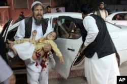 A man carries a wounded boy to a hospital after a car bombing outside a sports stadium in Lashkargah, capital city of southern Helmand province, Afghanistan, March 23, 2018. Provincial chief of police Abdul Ghafar Safi said the blast was carried out by a suicide bomber and that the target was civilians.