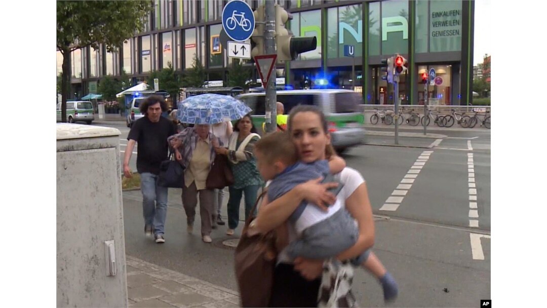 FILE - Members of the public run away from the Olympia Einkaufszentrum mall, after a shooting, in Munich, Germany, July 22, 2016.