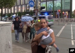 FILE - Members of the public run away from the Olympia Einkaufszentrum mall, after a shooting, in Munich, Germany, July 22, 2016.