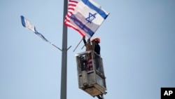 A worker hangs Israeli and American flags on a lamppost along a freeway leading to Jerusalem, days before a planned visit by President Donald Trump, May 16, 2017. 