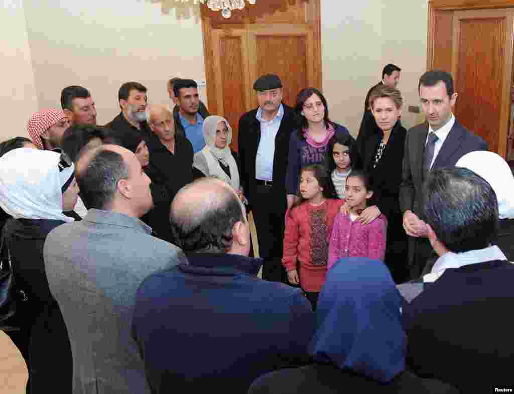 Syrian President Bashar al-Assad and his wife Asma visit families of students killed during clashes between forces loyal to him and their opponents in Damascus in this handout photograph released by Syria's national news agency SANA on March 20, 2013.